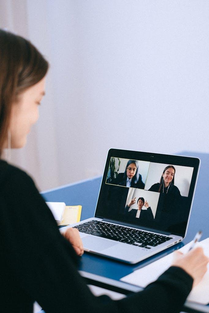 a woman participates in a virtual meeting with colleagues via video call on a laptop. 4226122 scaled